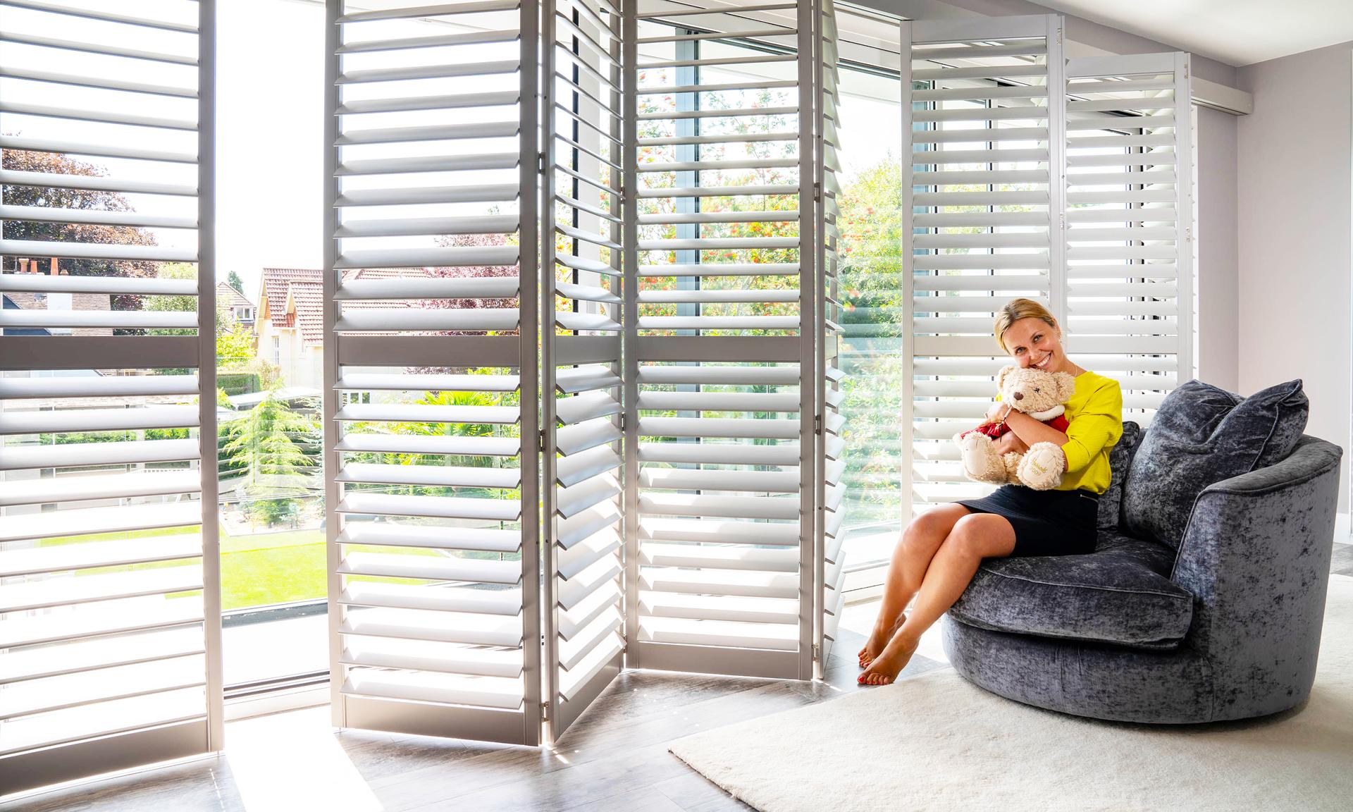 Woman smiling in front of white shutters
