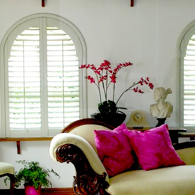 image of a white room with white window shutters and pink flowers and pillows